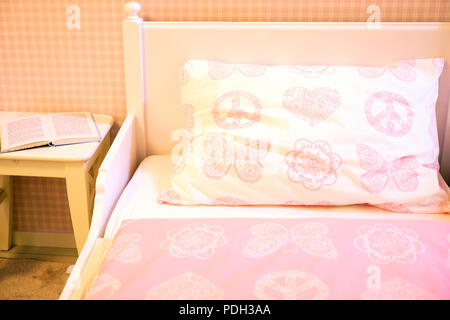 Children's room with pink walls, wooden floor, bed with pink pillow and blanket Stock Photo