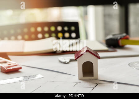 A architects house model with plan and blueprints on architect desk Stock Photo