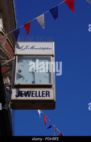 Jeweller Shop Clock on a Sunny Day with Red, White and Blue Bunting. Sidmouth, East Devon, UK. Stock Photo
