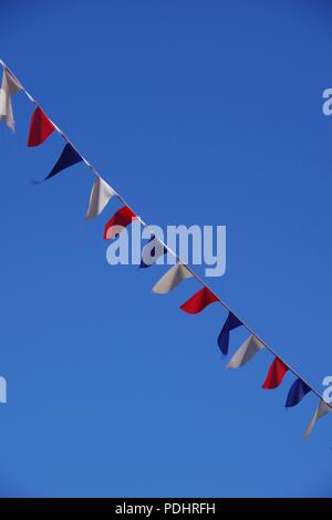 Red, White and Blue Bunting Flags Diagonally against a Blue Summer Sky. Sidmouth Folk Festival, East Devon, UK. Summer, 2018. Stock Photo