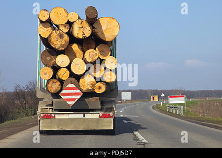 Logging lorry carry wooden logs at road Stock Photo