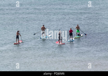 Paddle boarders near seven sisters cliffs UK on a hot Saturday morning 2018 summertime heatwave calm sea hot sun gentle water sport activity. Stock Photo