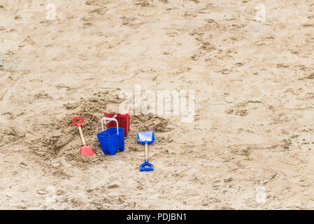 Colourful plastic buckets and spades on a sandy beach. Stock Photo