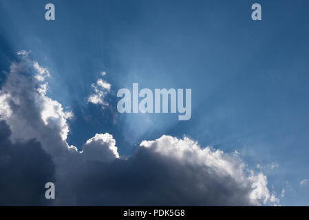 Sun rays behind dark thunderstorm clouds Stock Photo
