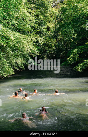 Munich, Germany - July 29, 2018: Swimmers on the fast moving Eisbach, a small man-made 2km long fast rapids inside the English Gardens, Munich Stock Photo