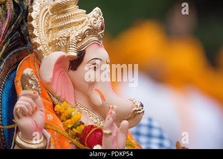 An idol with a divine profile of Lord Ganesha the elephant-headed Hindu God son of Lord Shiva and Parvati with a golden headgear and a flower garland Stock Photo