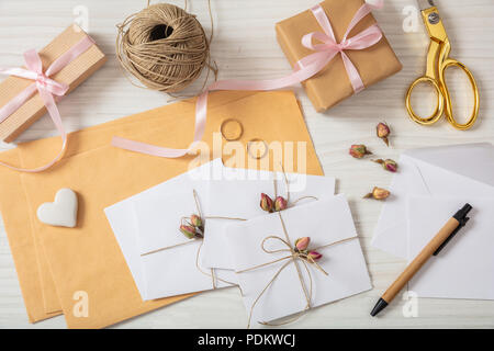 Wedding preparation. Flat lay and top view of presents and wedding invitations on a white wooden tabletop, background. Stock Photo
