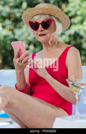 Blonde-haired mature woman wearing red swimming suit sunbathing Stock Photo
