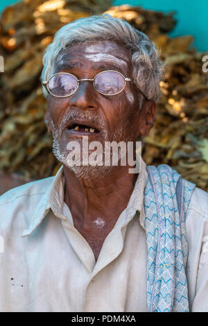 Nilavagilukaval, Karnataka, India - November 1, 2013: Closeup of old graying man with open mouth showing bad brown teeth. Wears circular glasses and d Stock Photo