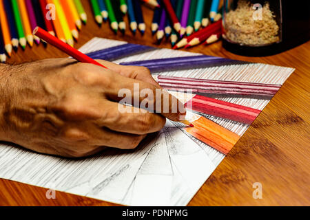 An Artists hand at work using colored pencils to draw colored pencils on white paper.  there is negative space for Copy. Stock Photo