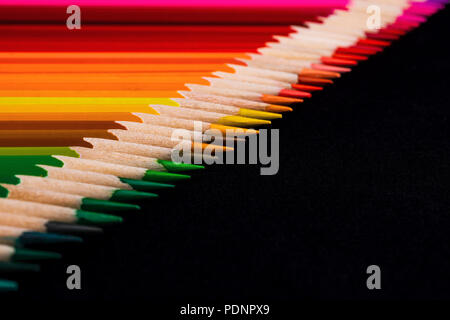 A macro image of a diagonal line of colored pencil sharpened tips with plenty of Black negative space for copy.  The line is very ordered and laid out Stock Photo