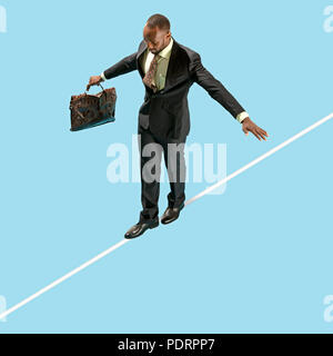 Business man on tightrope concentrate to walking isolated on blue background. Business, career, risk concepts Stock Photo