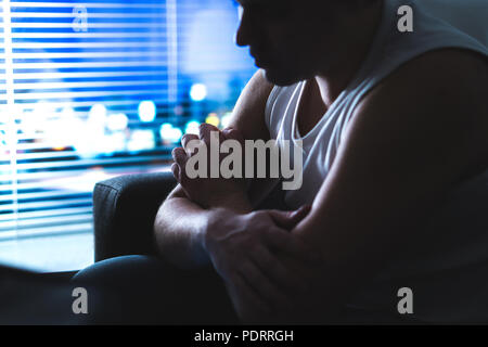Thoughtful, pensive and contemplating man thinking in dark home at night by the window. Emotional and dramatic mood. Making hard decision. Stock Photo