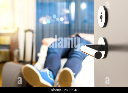 Tired traveler sleeping on hotel room bed. Exhausted man after long flight and travel with baggage. Tourist arrived home from vacation. Stock Photo