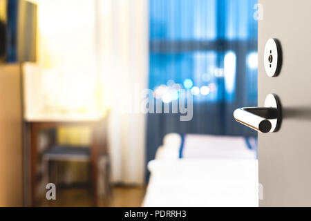Hotel room door open. Clean and elegant accommodation service. Close up of handle. Bed, table and tv. Travel, lodging and motel concept. Stock Photo