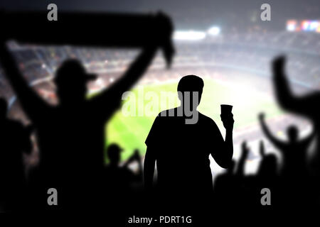 Football fan drinking beer in crowd in stadium. Man with alcohol beverage in soccer audience at a game. Holding pint. Drunk person in live sport event Stock Photo