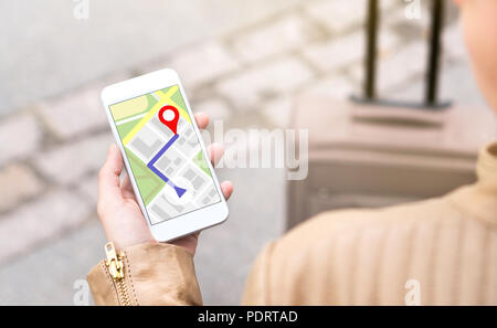 Woman navigating with mobile phone map application. Tourist with walking route on smartphone screen. Traveler with baggage using GPS. Stock Photo