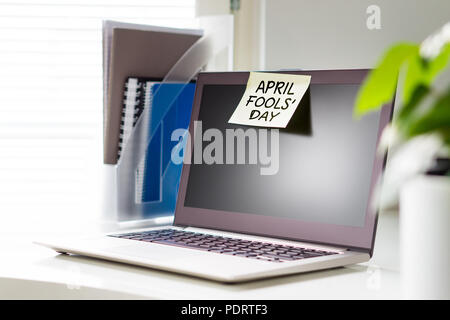 April Fools' Day note on laptop at work. Yellow sticky note on computer in office. Stock Photo