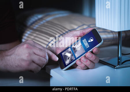 Man using home security system and application in smartphone. Watching protection and surveillance camera live footage inside a house or apartment. Stock Photo