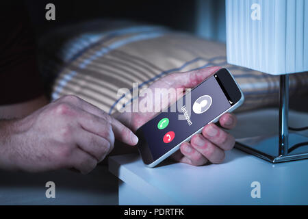 Unknown number calling in the middle of the night. Phone call from stranger. Person holding mobile and smartphone in bedroom bed home late. Stock Photo