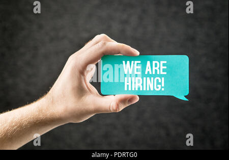 We are hiring text on speech balloon held by hand on dark background. Recruitment, human resources and employment concept. Labour wanted. Stock Photo