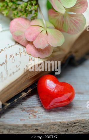 rotes Herz auf Buch mit alter Schrift