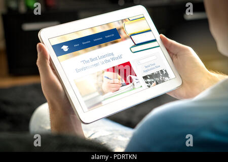 School website on tablet screen. Young man and applicant browsing college or university websites before applying. Stock Photo