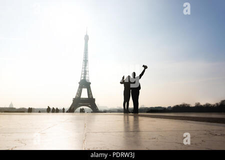 Couple at Eiffel Tower. Travelers and tourists exploring the world and the city of Paris. Romantic lovers on honeymoon or friends having fun. Stock Photo