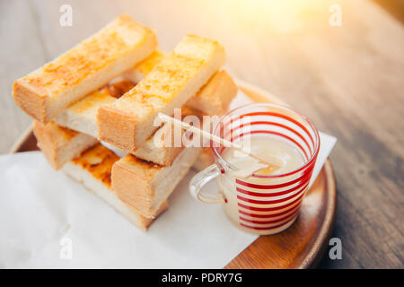 Toast white bread sliced with Sweet condensed milk for dipping on wooden table taste yummy and fat Stock Photo