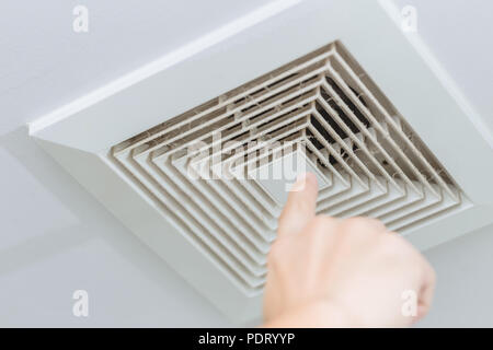 Finger pointing at dusty dirty ceiling air ventilation fan hole grill duct for cause of lung disease Stock Photo