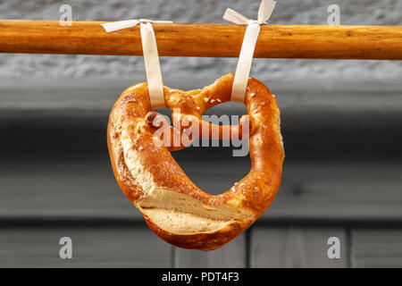 A pretzel or brezel in German hanging on a wooden bar, typical Bavarian food and beer snack Stock Photo