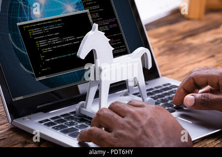 Close-up Of A Businessman Using Laptop With Trojan Horse On The Keypad Stock Photo