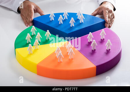 Businessperson placing last piece with human figures into colorful pie chart Stock Photo