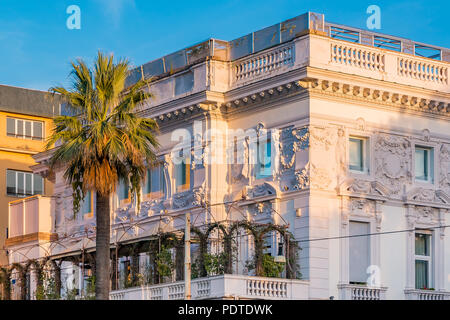 Ornate facade of an apartment building covered with ivy vines over a balcony at sunset in Rome, Italy. Stock Photo