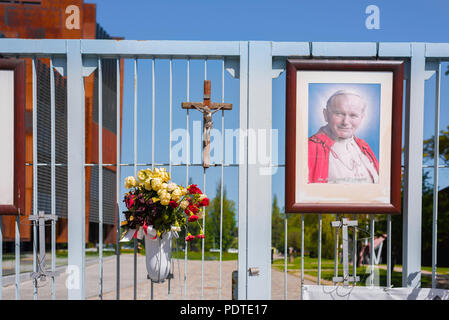 Portrait of Pope John Paul ll, crucifix and flowers fixed to the historic Number 2 Gate of the Gdansk shipyard, site of 1980s Solidarnosc protests. Stock Photo