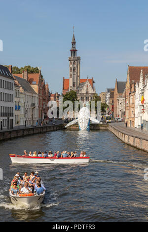 Tourists in a canal tour boat viewing the Bruges Plastic Whale sculpture made from discarded plastic containers and waste washed up from the sea,