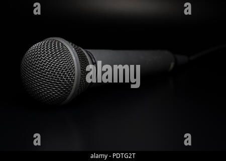 Singers Microphone close up. Macro picture of musical equipment. Black Mic on Black background. Stock Photo