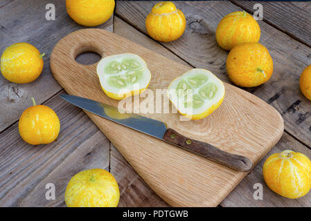 Lemon cucumbers, also known as Cucumis Sativus on a wooden chopping board with whole and cut fruit. Stock Photo