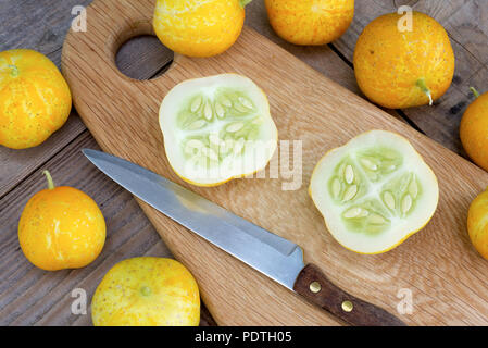 Lemon cucumbers, also known as Cucumis Sativus on a wooden chopping board with whole and cut fruit. Stock Photo