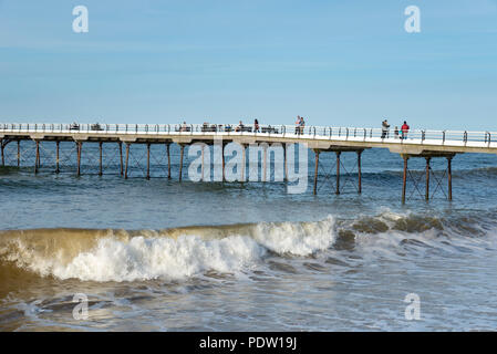 People enjoying a stroll along the old pier at Saltburn-by-the-sea on the coast of North Yorkshire, England. A lovely spring evening. Stock Photo