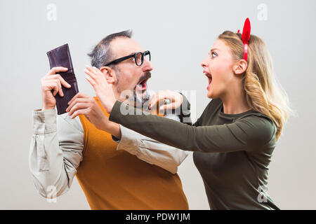 Nerdy man is trying to hide money from his wife because she want to spend it all. Stock Photo