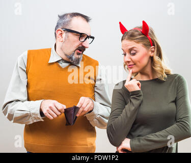 Nerdy man is uncertain,he is thinking does his wife love more him or his money. Stock Photo