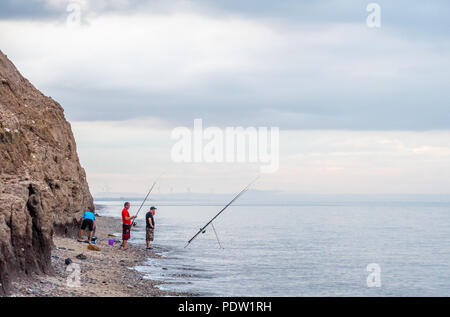 Sea anglers fishing from the beach at Skipsea, Yorkshire at high tide, Stock Photo