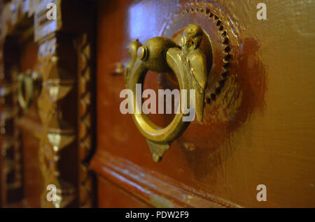 Ancient vintage bronze metal handle on a brown polished door Stock Photo