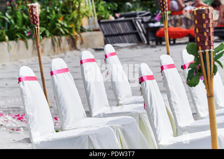 Wedding chairs, Spandex white cover decorating with red pink organza sash line up for beach wedding venue settings Stock Photo