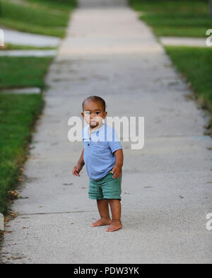 Toddler boy navigates a sidewalk. Stock Photo