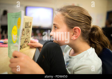 A fourth grade girl reads a graphic novel in a Wisconsin classroom. Stock Photo