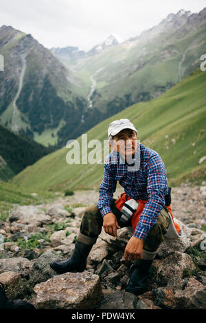 Kyrgyz man hiking in the mountains in Karakol Stock Photo