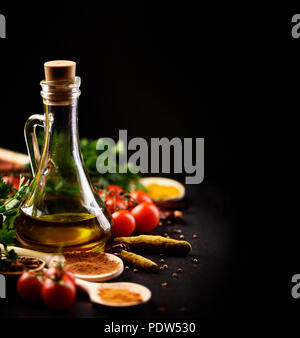 Olive oil and various spices on black rustic background Stock Photo