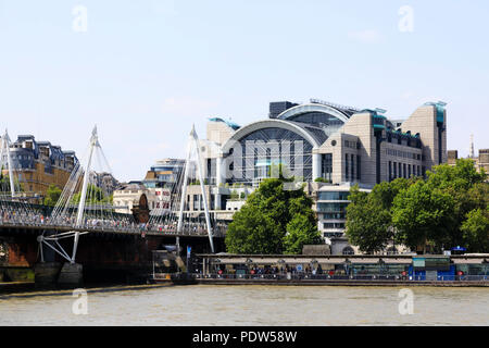 Charing Cross railway station on the north bank of the River Thames, London. Hungerford and Golden Jubilee bridge with crowds of tourists. Stock Photo